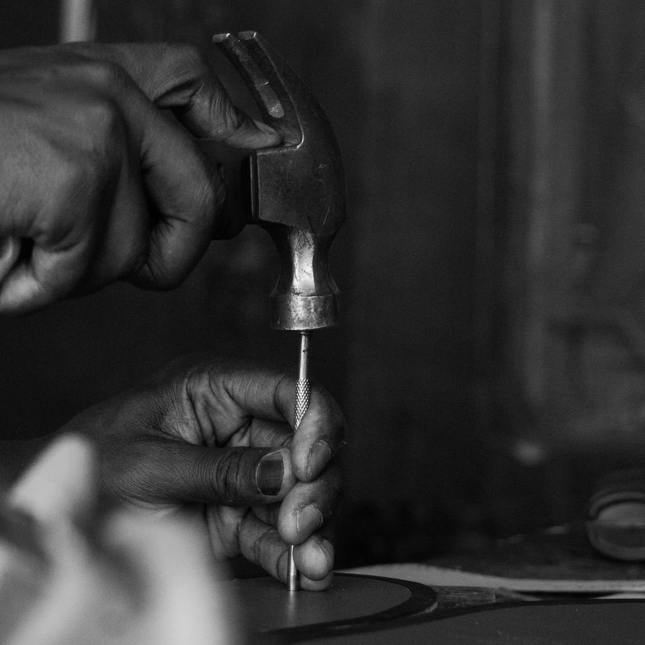 Close-up of hands using hammer and chisel, showcasing craftsmanship.