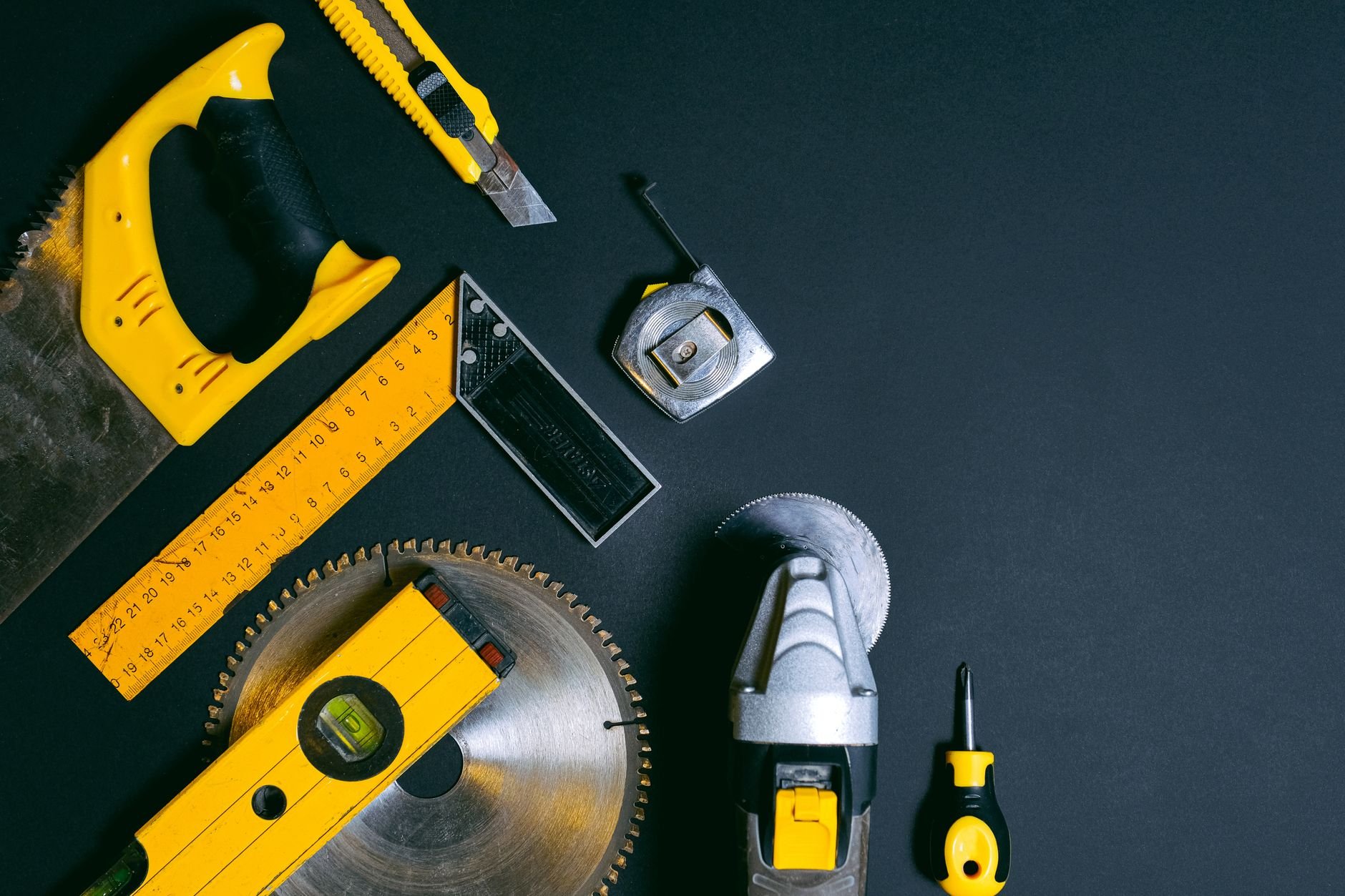 A collection of construction tools arranged on a dark surface.